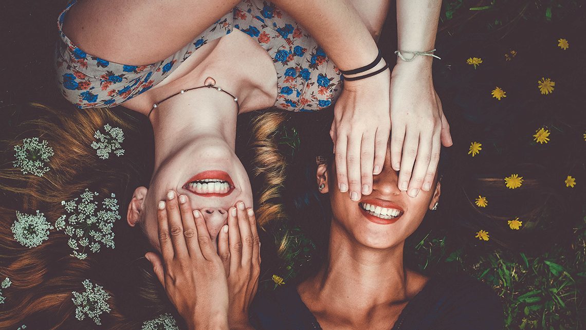 Photo de deux filles allongées qui se mettent les mains devant les yeux